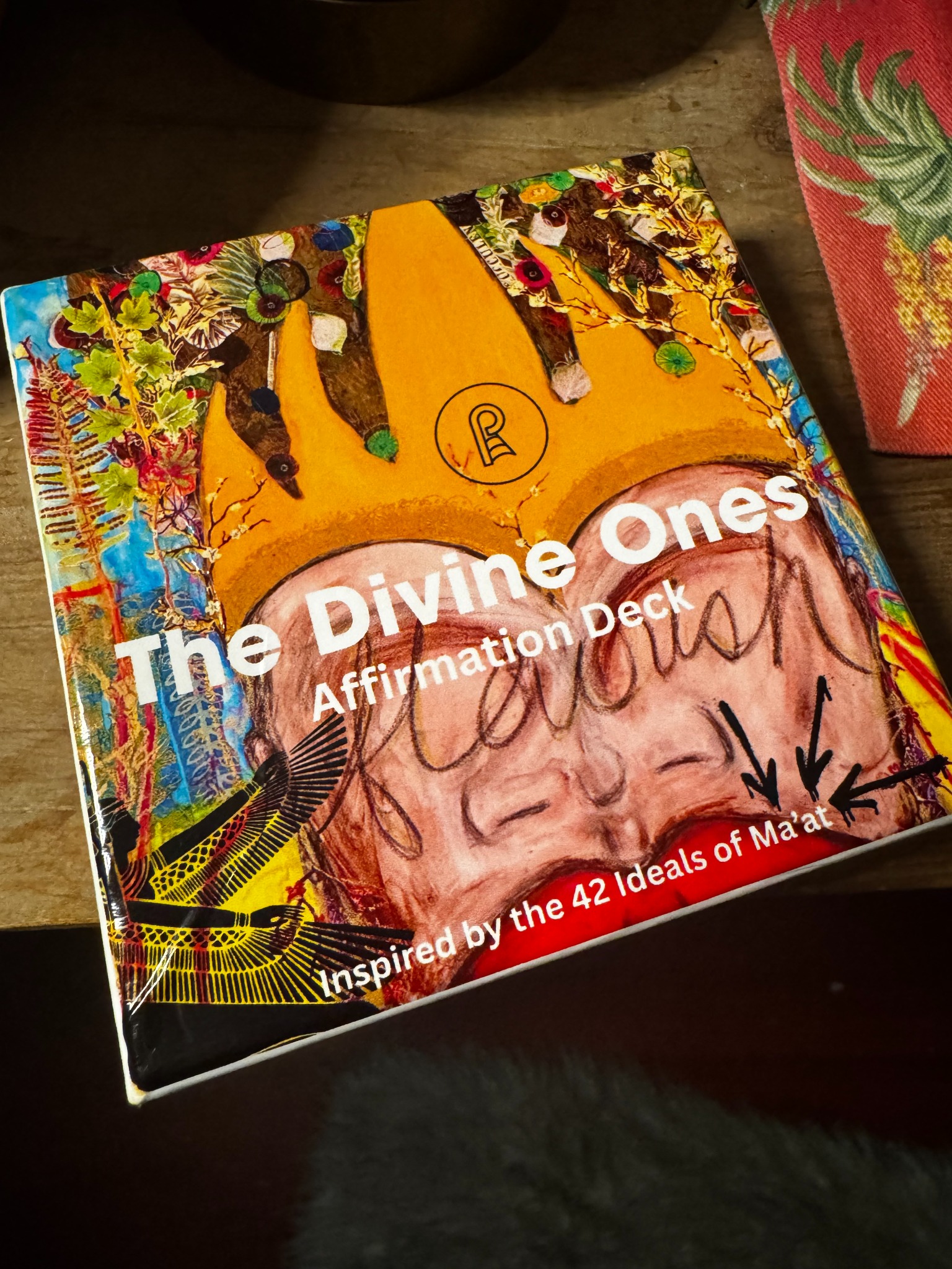 The Divine Ones Affirmation Deck box featuring Tye’s crowned figurative artwork and the words Inspired by the 42 Ideals of Ma’at