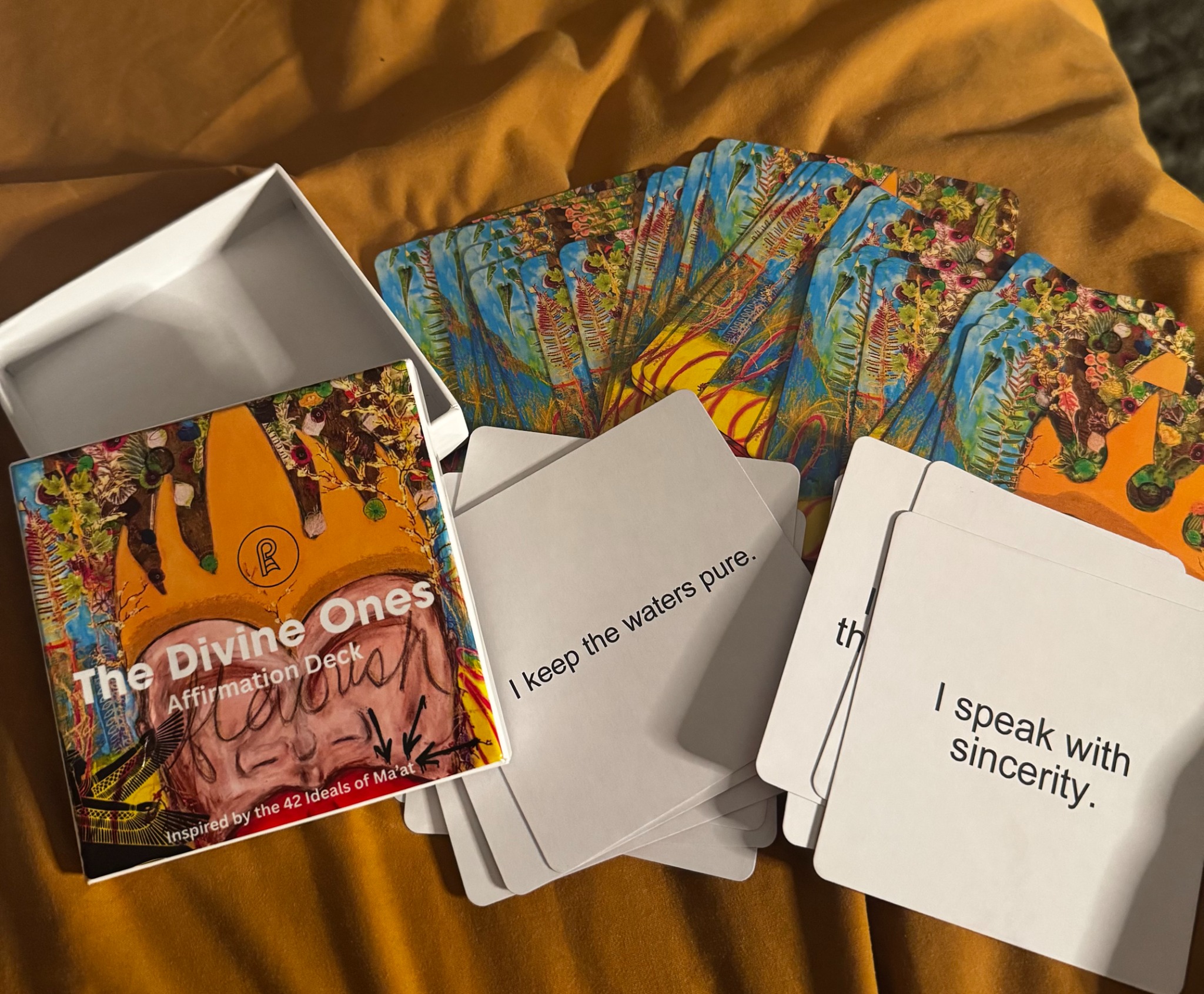 The Divine Ones Affirmation Deck with colorful botanical card backs and cards reading I keep the waters pure and I speak with sincerity